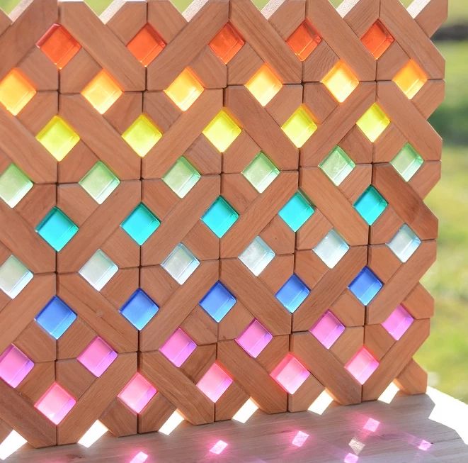 Bauspiel X-Blocks built into a lattice wall with colored lucent cubes glowing in the openings