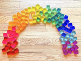 Bauspiel Lucent Cubes laid out in a rainbow arc on a wooden floor · view 6