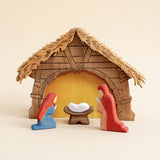 Wooden nativity scene in a thatched stable with the holy family inside · view 1