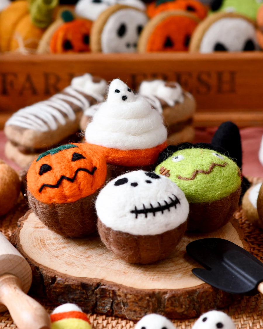 Four felt Halloween cupcakes topped with a ghost, a green monster, a white skull, and a jack-o-lantern