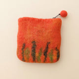 The back of the orange felt purse, with green and brown grass felted along the bottom · view 2
